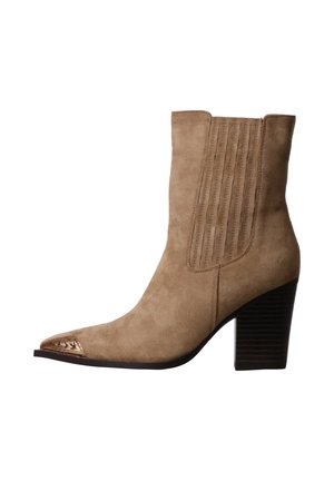 Bottine cheville en daim beige avec talon bloc empilé et empiècement élastique cousu, avec détail métallique sur l’embout pointu.