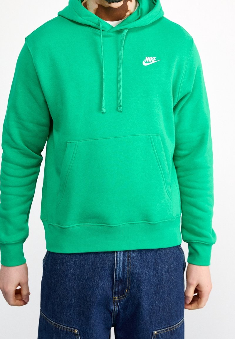 Grön Nike-hoodie i mjukt tyg, med en framficka, dragsko på huvan och en liten vit Nike-logga på bröstet.