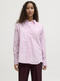 Light pink button-up shirt with a pocket, relaxed fit, and long sleeves. Made of smooth fabric with a curved hem. Paired with dark trousers.