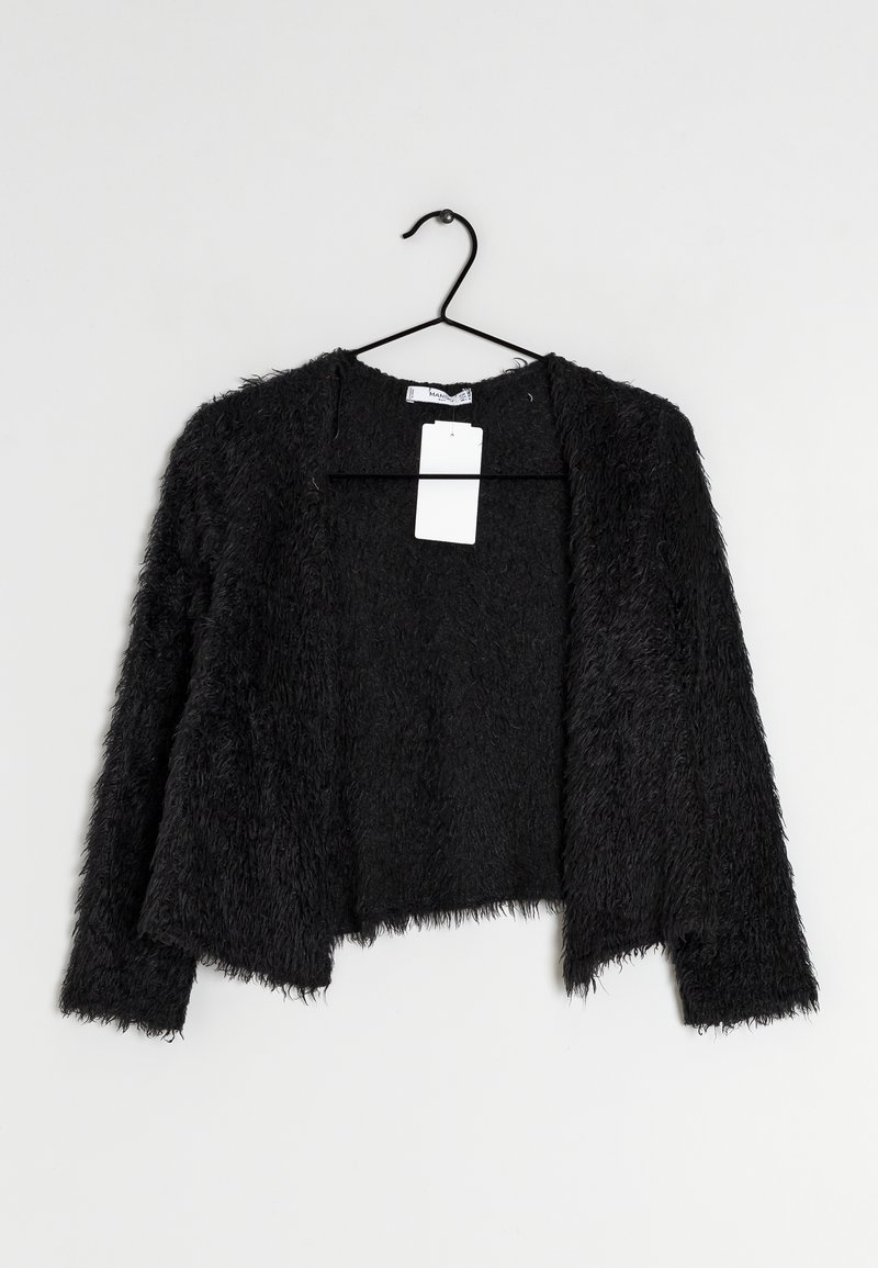 Cardigan noir en peluche avec un design court, présentant des manches longues et une ouverture devant. La texture du matériau est douce et duveteuse. Étiquette visible à l'intérieur.