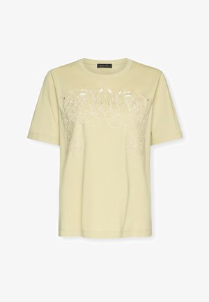 T-shirt crème à manches courtes avec col rond et broderie florale subtile sur la poitrine et le haut des manches.