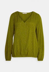 Blusa verde oliva con mangas largas, escote en V y bajo elástico. Decorada con pequeños puntos negros y grises. Textura de tejido suave.