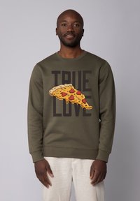 Olijfgroen sweatshirt met een grote afbeelding van een pizzastuk met hartvormige toppings en de tekst "WAAR LIEFDE" in dikke zwarte letters.