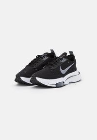 Czarne buty sportowe z siateczkową cholewką, białymi akcentami, okrągłym noskiem i teksturowaną czarną podeszwą. Posiadają wyraźne logo swoosh po bokach.