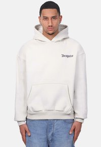Cream hoodie with a kangaroo pocket, ribbed cuffs, and hem; features "Dropsize" embroidered in dark blue on the chest. Worn with light blue jeans.