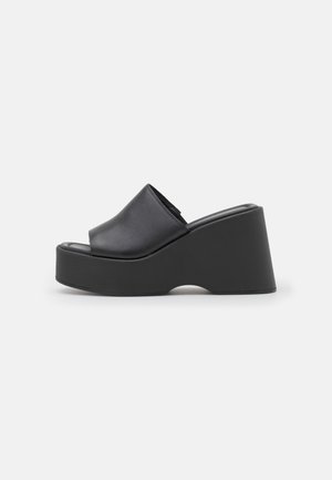 Sort platform kile-sandal med åben tå og bred rem på ensartet lys baggrund, sidevisning.