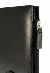 Czarny skórzany portfel o gładkiej fakturze, z zamkiem błyskawicznym i precyzyjnym przeszyciem na brzegach. Posiada metalowy suwak.