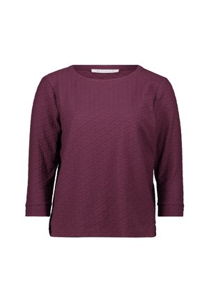 Top a maniche lunghe color bordeaux con un motivo testurizzato, scollo rotondo e orlo leggermente curvo. Il materiale sembra morbido e elasticizzato.
