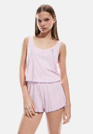 Ensemble de pyjama deux pièces rose clair en tissu côtelé. Le haut présente un décolleté arrondi et un petit design brodé ; le short a un ourlet volanté.