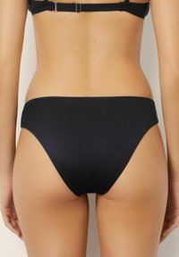 Zwarte bikini onderstukken met een hoge snit en een gladde textuur, gekenmerkt door een minimalistische stijl zonder zichtbare hardware of patronen.