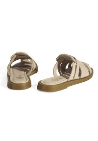 Sandales beiges avec un design à plusieurs brides et une semelle rembourrée. Fabriquées en matériau synthétique avec une forme plate et flexible, et une texture subtile.