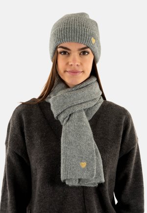 Harmaa neulepipo ja siihen sopiva huivi, joissa on ribbitekstuuri ja pieni kultainen sydänkoriste, käytetään tumman neuleen päällä.