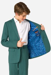Completo teal con pantaloni abbinati, chiusura a bottone e una camicia bianca. L'interno presenta un motivo blu con design astratti e un accento arancione.