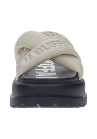 Sandales beige à brides croisées avec une épaisse semelle noire. Bride supérieure texturée avec des lettres en relief. L'intérieur présente un détail de logo blanc.