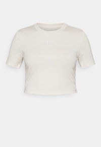 Krótki rękaw, krótka koszulka z lekkiej bawełny w kolorze jasnobeżowym, z subtelnym logo Nike w jasnym fioletowym kolorze umieszczonym na środku klatki piersiowej.