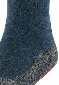 Calcetín de lana azul con una parte superior texturizada, talón gris con patrón y un acento rojo. Diseñado para ofrecer comodidad y ajuste durante actividades al aire libre.