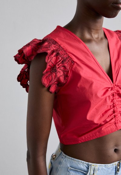 Rød crop top med v-hals og samlet front, med volangermer utsmykket med blomsterbroderi og blonder.