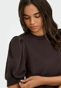 Brown puff-sleeve sweater made of soft fabric with a ribbed neckline. Features a relaxed fit and gathers at the sleeve hems.