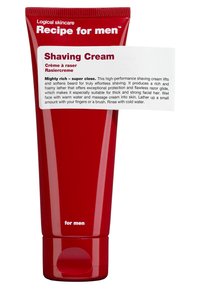 Tube rouge en plastique de crème à raser avec une étiquette blanche. L'étiquette mentionne la performance, la mousse onctueuse et l'adéquation pour les poils faciaux épais.