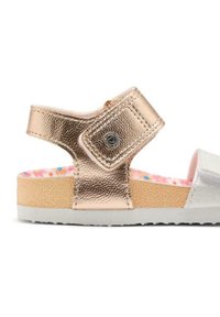 Sandaña con strap en metalizado color rosa dorado, suela de corcho texturizada y plantilla suave y colorida con un patrón floral. Detalle blanco en la punta.