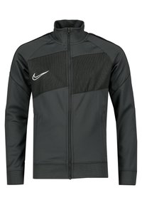 Veste de sport noire avec un col haut, fermeture éclair à l'avant, panneau en maille sur la poitrine, arborant le logo swoosh de Nike en blanc sur le côté gauche.