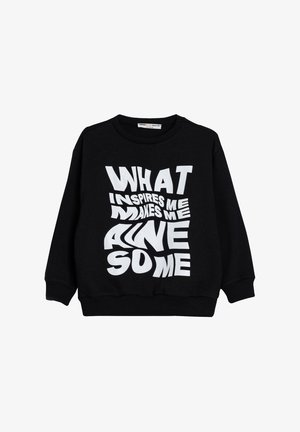 Czarna bluza z bawełny z wyraźnym białym napisem "CO MNIE INSPIRUJE, CZyni Mnie WSPANIAŁYM" w różnych zniekształconych czcionkach.