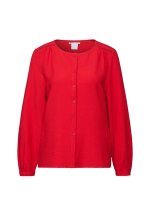 Rode blouse met lange mouwen en een gestructureerde afwerking, ronde halslijn en knopen aan de voorkant. Heeft subtiele plooien bij de schouders.