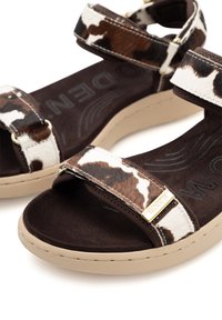 Brown and white cowhide sandals with fabric straps, beige soles, and gold hardware detail. Textured insole with ridged logo design.