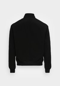 Veste bomber noire à manches longues avec poignets côtelés, ceinture et col montant, vue de dos sur fond clair.
