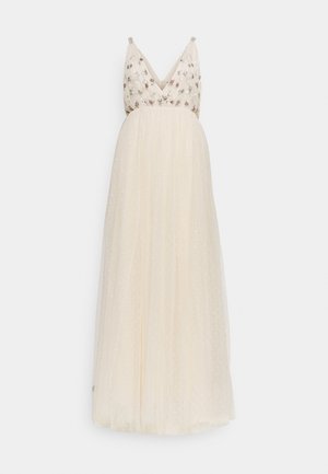 Langes cremefarbenes ärmelloses Kleid mit V-Ausschnitt, verziertem floralen Oberteil und fließendem, transparentem Rock mit subtilem Pünktchenmuster.