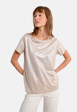 T-shirt a maniche corte, di un leggero color beige chiaro, con una texture lucida e riflettente. Presenta un colletto rotondo e una vestibilità rilassata. Tessuto morbido con cuciture minime.