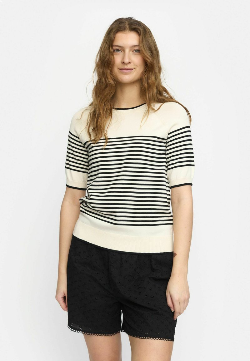 Cremfarbener und schwarzer, gestreifter Strickpullover mit kurzen Ärmeln und geripptem Saum, kombiniert mit schwarzen, strukturierten Shorts mit gewelltem Saum.