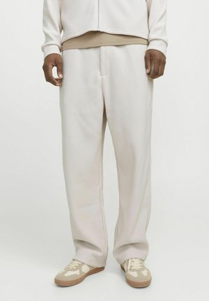 Beige ribbede bukser med en afslappet pasform, der har en elastisk talje og sidelommer, parret med lysebrune sneakers.