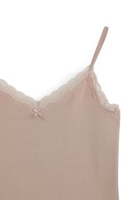 Camisola nuda con spalline regolabili, caratterizzata da un bordo di pizzo ondulato sullo scollo e un fiocco di raso sul davanti. Texture liscia.