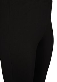 Mustad mustadest kangast retuusid, millel on sile tekstuur ja kehaümberpaiknev disain, ilma nähtavate aktsentide või mustriteta.