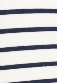 Hvidt stof med brede marineblå vandrette striber. Teksturen er strikket og præsenterer et ensartet mønster over det hele.