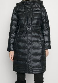 Svart puffjacka med glänsande yta, med bälte vid midjan, fickor med dragkedja och knapp, samt en hög krage med knappdetaljer.