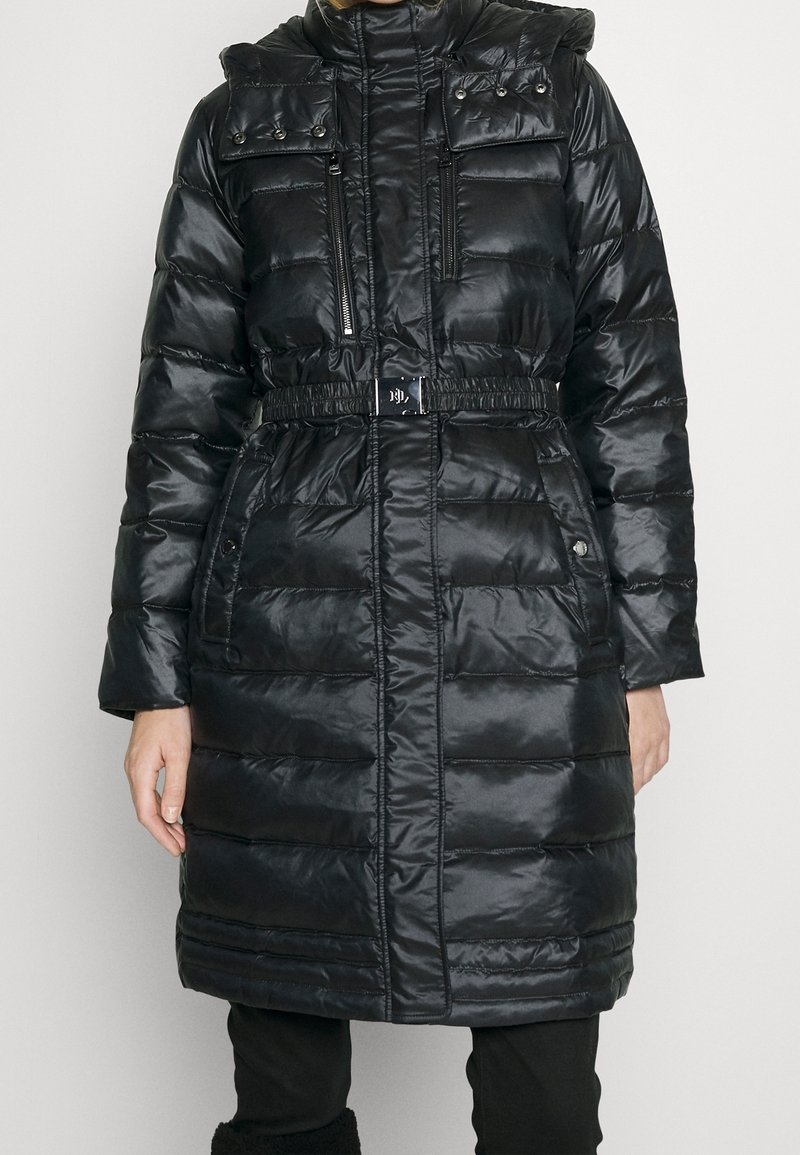 Svart puffjacka med glänsande yta, med bälte vid midjan, fickor med dragkedja och knapp, samt en hög krage med knappdetaljer.