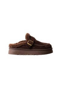 Chaussure marron sans lacets avec semelle épaisse, doublure en peau de mouton et détail de bride à boucle sur le côté.