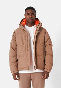 Bruine pufferjas met een gequiltde textuur en oranje binnenvoering. Beschikt over een capuchon en een sluiting met drukknopen aan de voorkant, met logodetail op de borst.