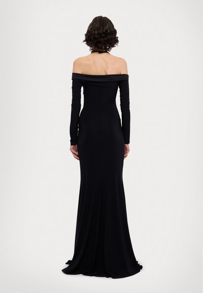 Robe noire décolletée avec manches longues, silhouette ajustée et jupe fluide. Un tissu lisse tombe élégamment depuis la taille.