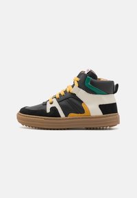 Hoge sneakers met zwarte leren en suède, witte en oranje accenten, gele veters, groene details en een bruine rubberen zool.