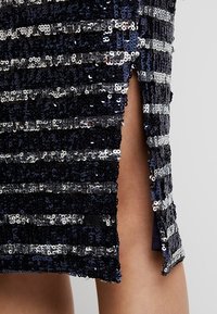Navy dress with sequins in horizontal stripes of silver and black, featuring a side slit and a textured finish.