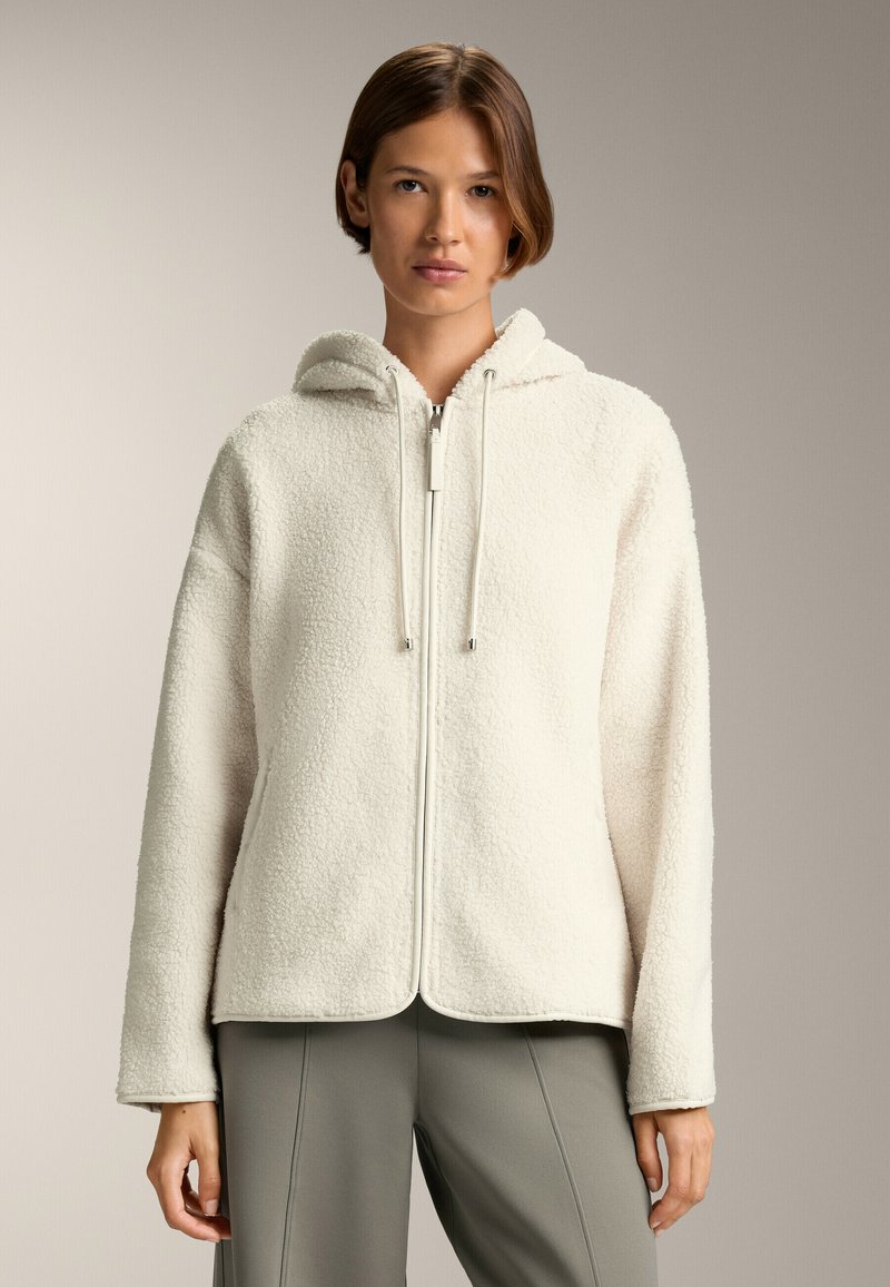 Giacca di pile color crema con cappuccio, zip frontale e cordini. Presenta una superficie testurizzata e una vestibilità rilassata per il massimo comfort.