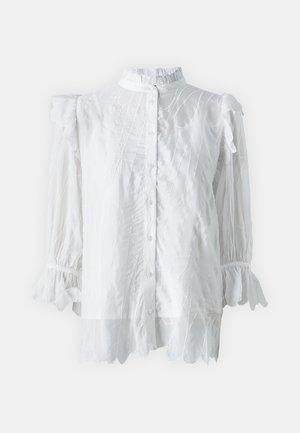 Blusa bianca con colletto e polsini a balze, caratterizzata da una chiusura frontale con bottoni e un motivo testurizzato sottile. Tessuto semitrasparente e maniche svasate.