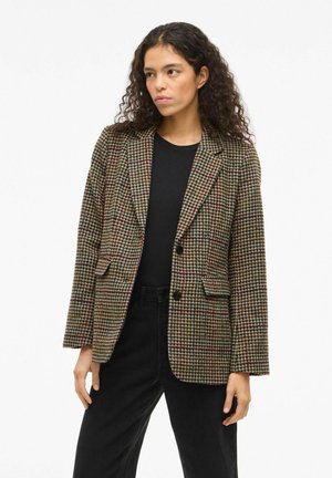 Blazer im Hahnentrittmuster in Braun, Grün und Rot mit taillierter Passform, mit Reverskragen und zwei Vorder pockets, getragen über einem schwarzen Oberteil.