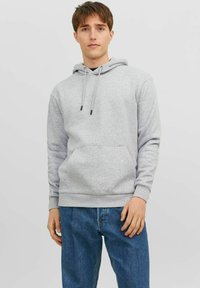 Gray cotton hoodie with adjustable drawstrings, front pocket, and ribbed cuffs, worn with blue denim jeans. Simple, casual design.