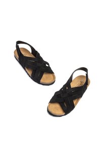 Sandales en daim noir avec un design entrecroisé, semelle en liège et semelle en caoutchouc. Dotées d'un dos ouvert et d'une sangle pour un ajustement sécurisé.