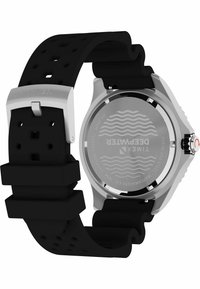 Montre avec bracelet en caoutchouc noir et boîtier en acier inoxydable. Ses caractéristiques incluent un design sportif, un bracelet texturé et un fond gravé avec les détails de résistance à l'eau.