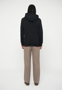 Felpa navy con un ampio cappuccio, maniche raglan e polsini a coste, abbinata a pantaloni larghi color marrone chiaro in un tessuto testurizzato.